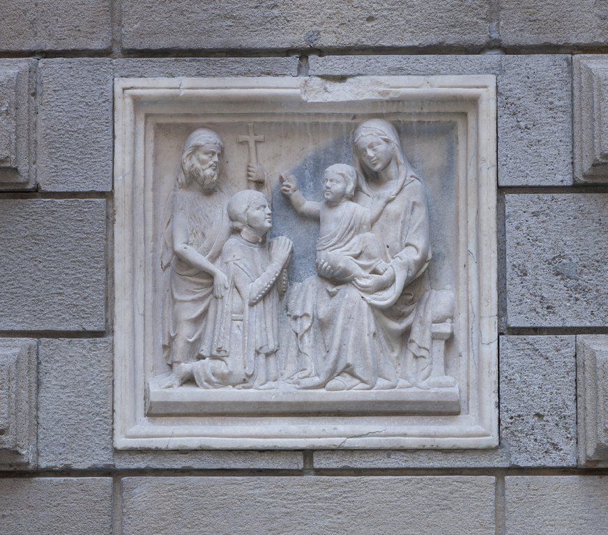 Una scultura in pietra di Gesù e della sua famiglia su un muro di mattoni