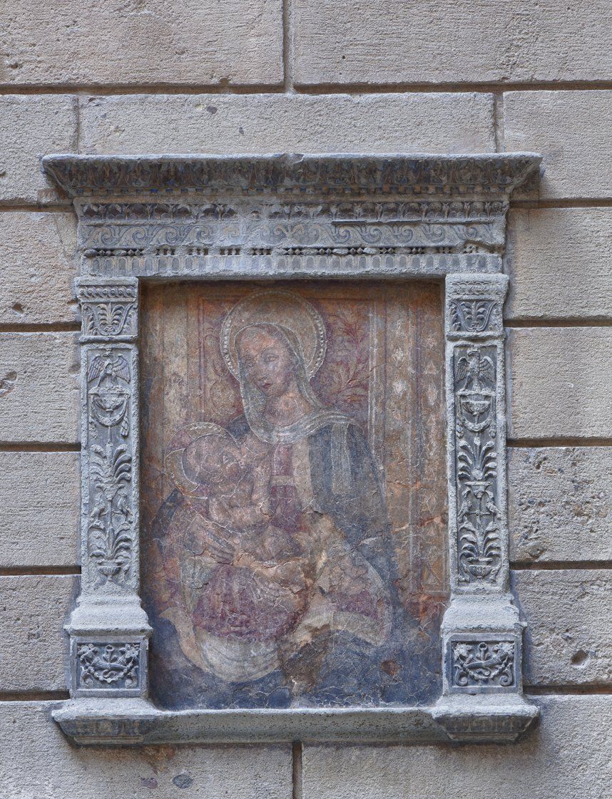 Un dipinto di Gesù e Maria in una cornice di pietra su un muro di mattoni.