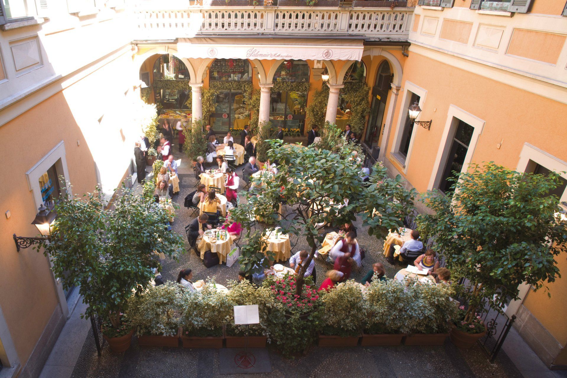 Un gruppo di persone è seduto ai tavoli di un cortile