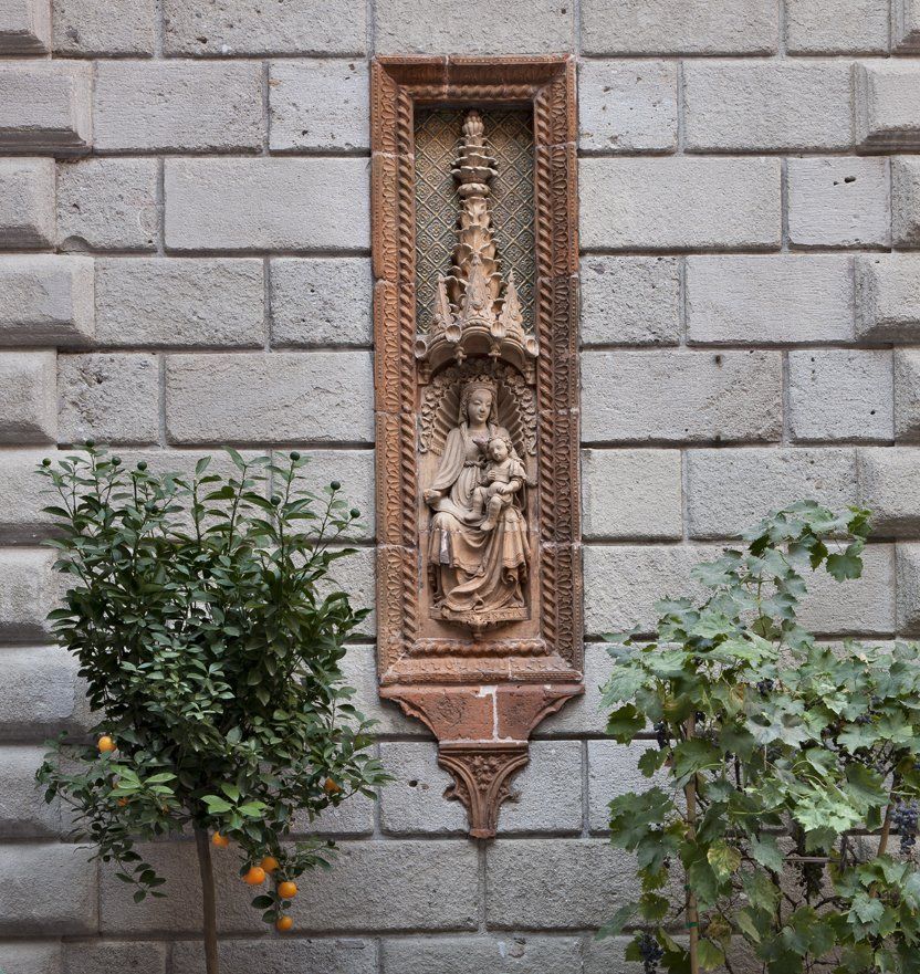 Una statua di una donna che tiene in braccio un bambino è su un muro di mattoni