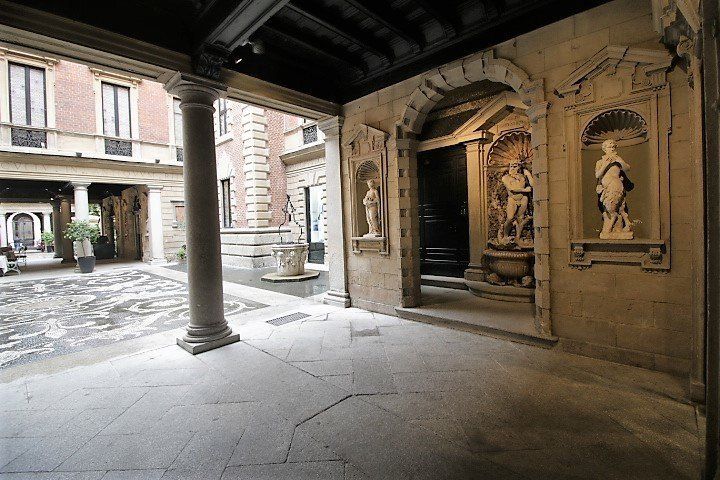 Un cortile con colonne e statue sulle pareti di un edificio.