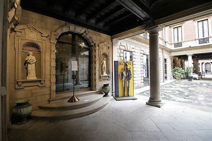 Un cortile con colonne e statue davanti ad un edificio.