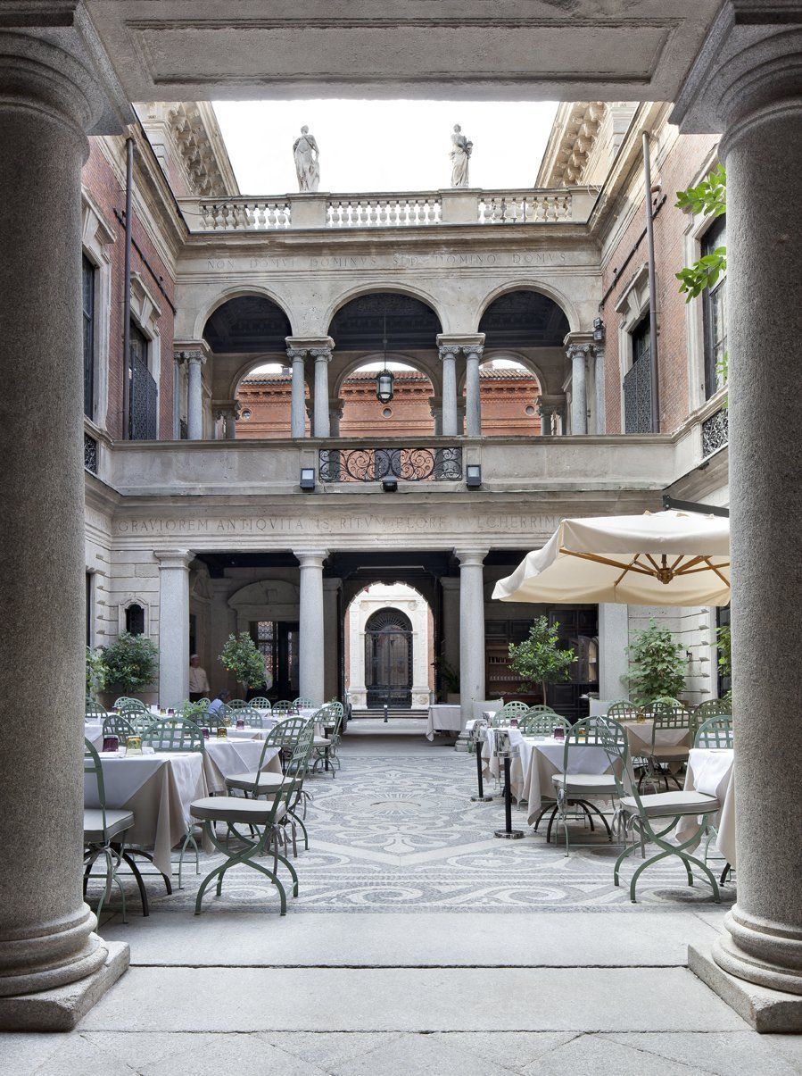 Un cortile con tavoli, sedie e ombrelloni