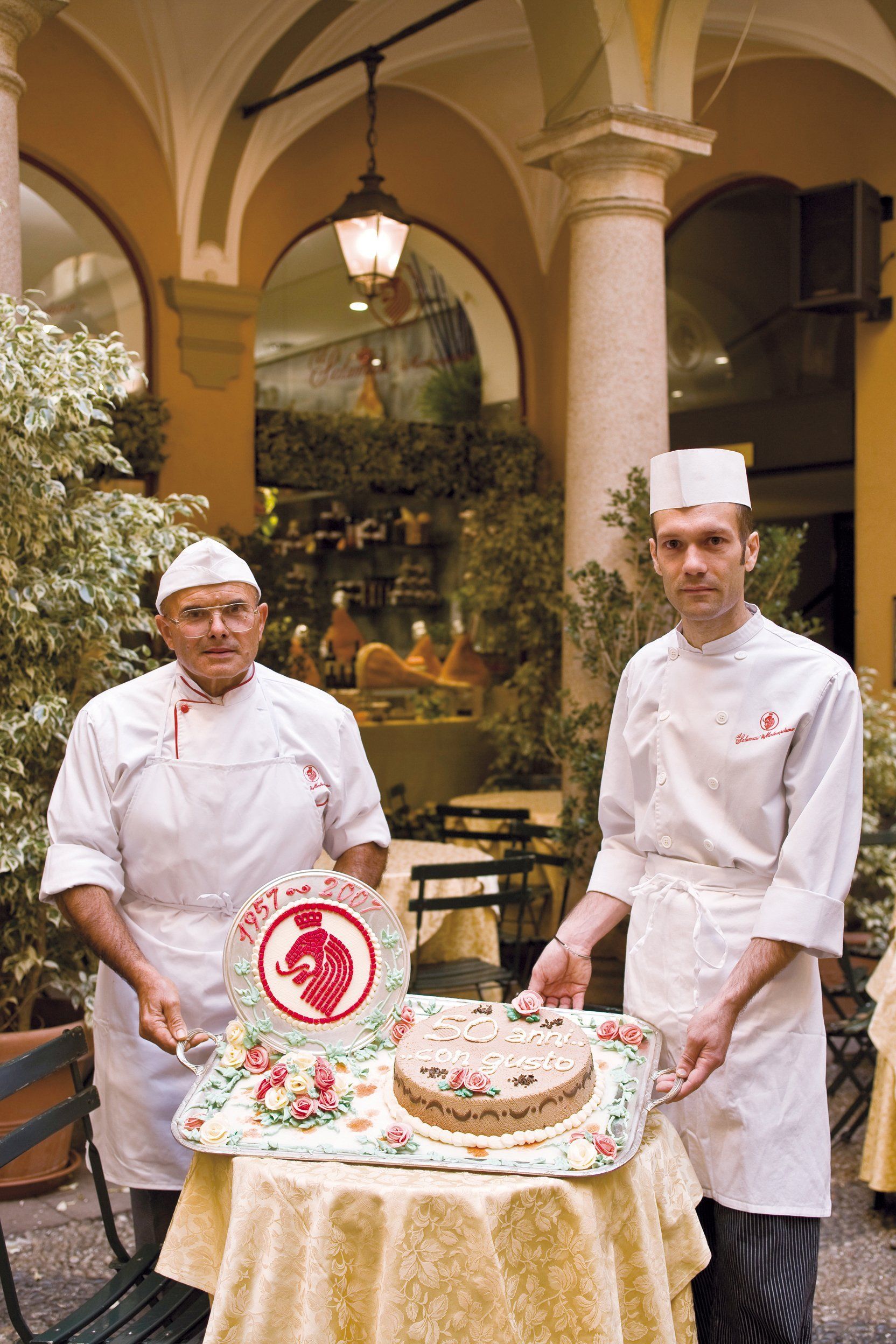 Due chef in piedi accanto a una torta su un tavolo