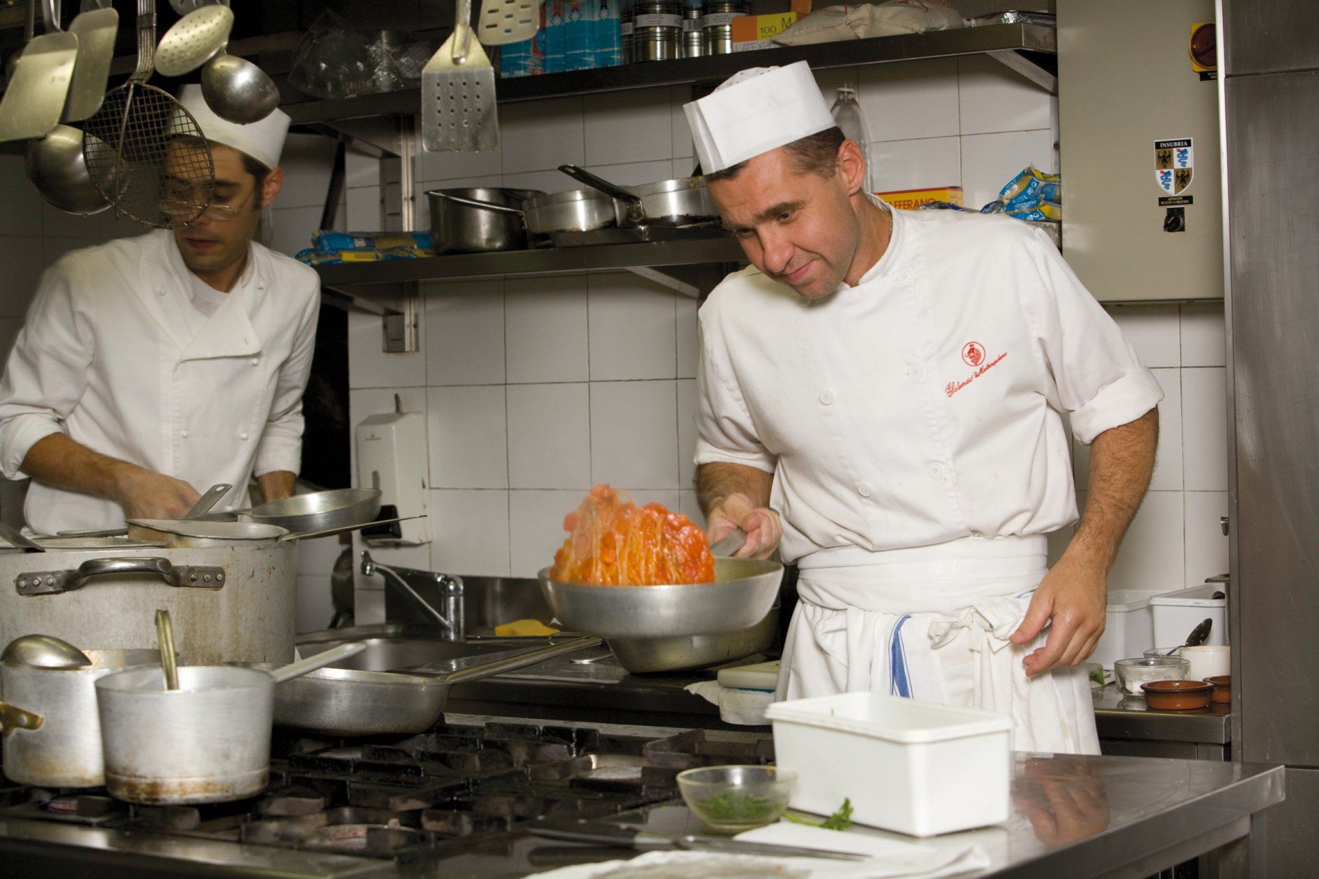 Due chef stanno preparando il cibo in una cucina.
