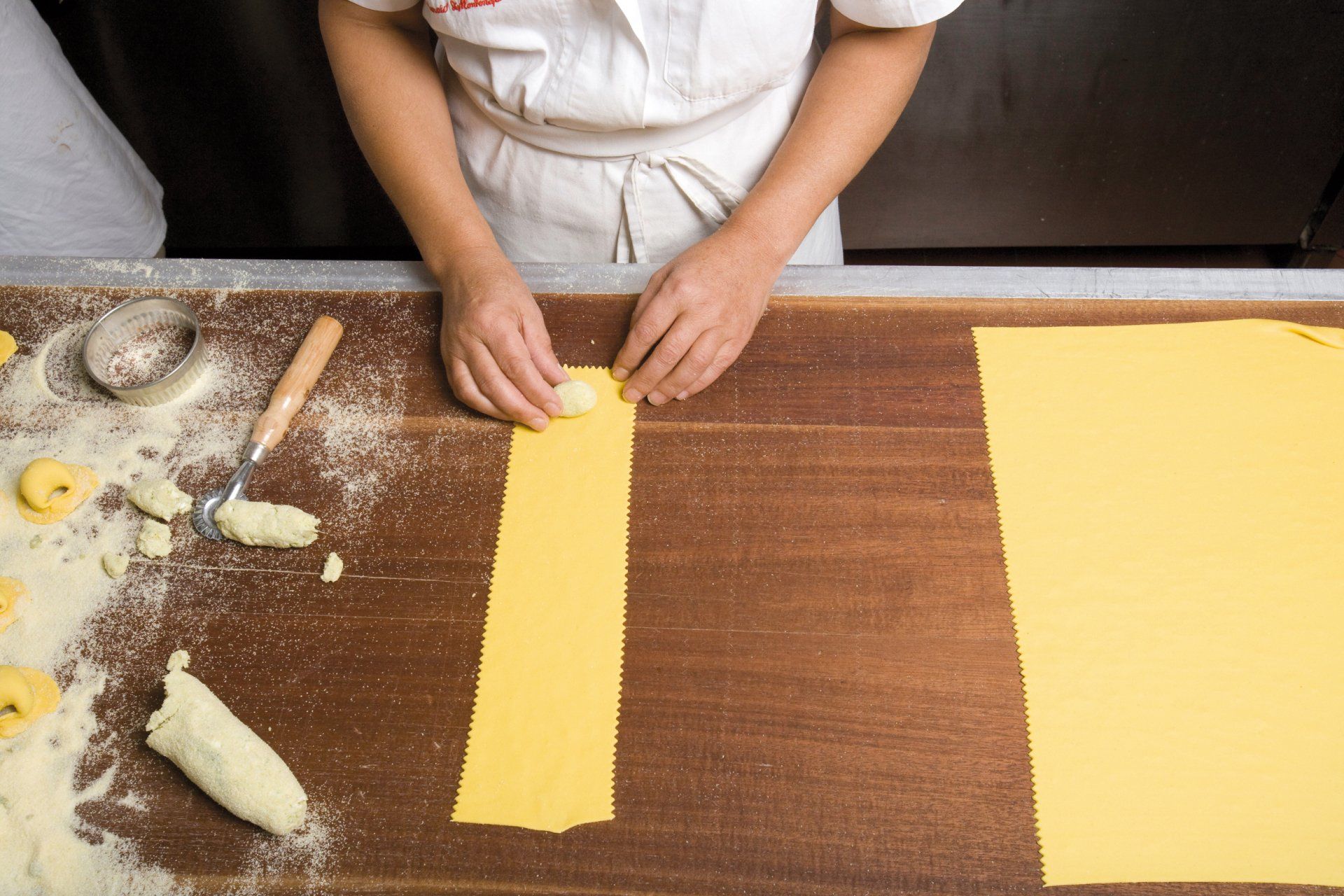 Una persona sta tagliando le tagliatelle su un tavolo di legno