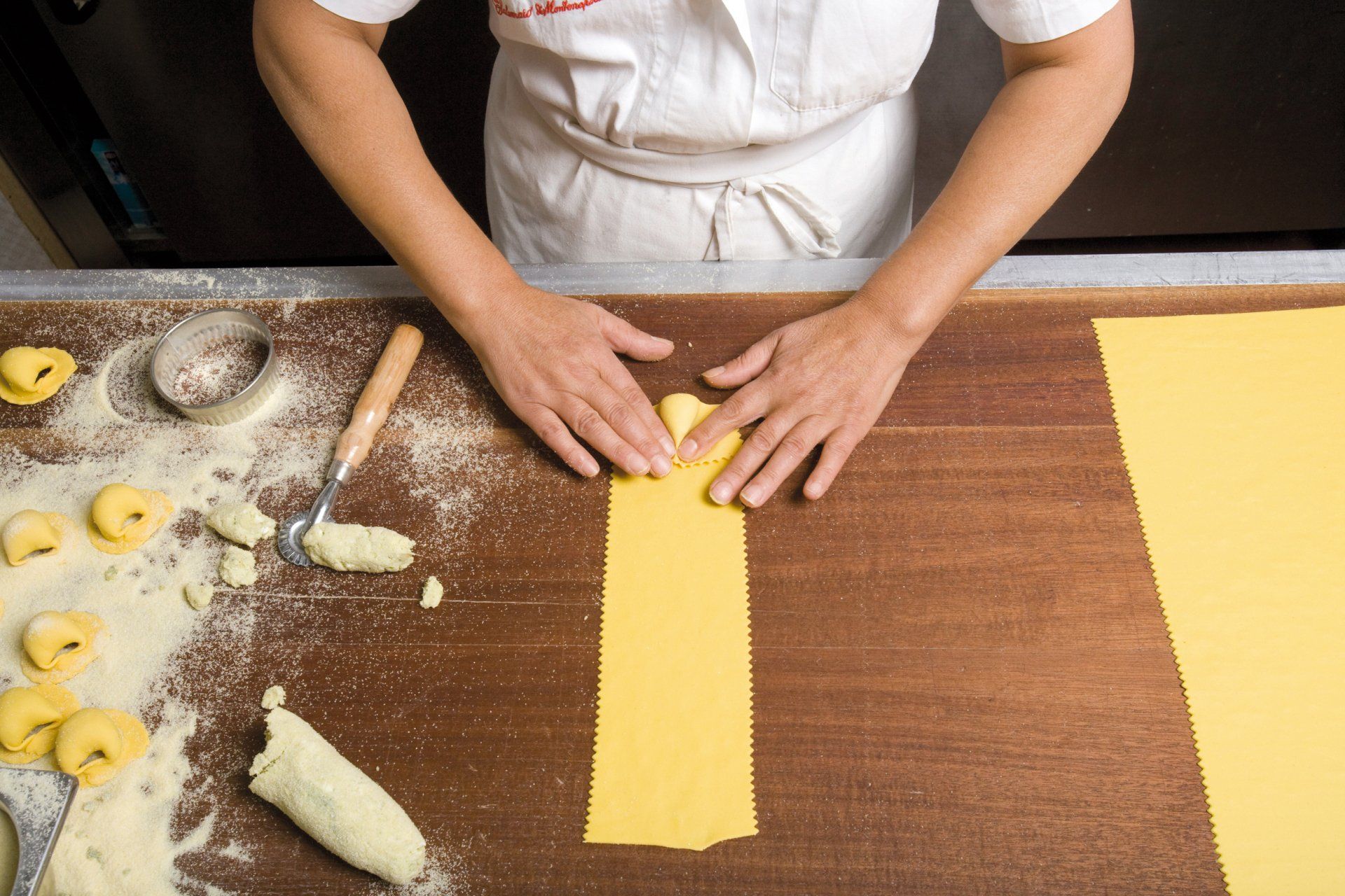 Una persona sta preparando la pasta su un tavolo di legno