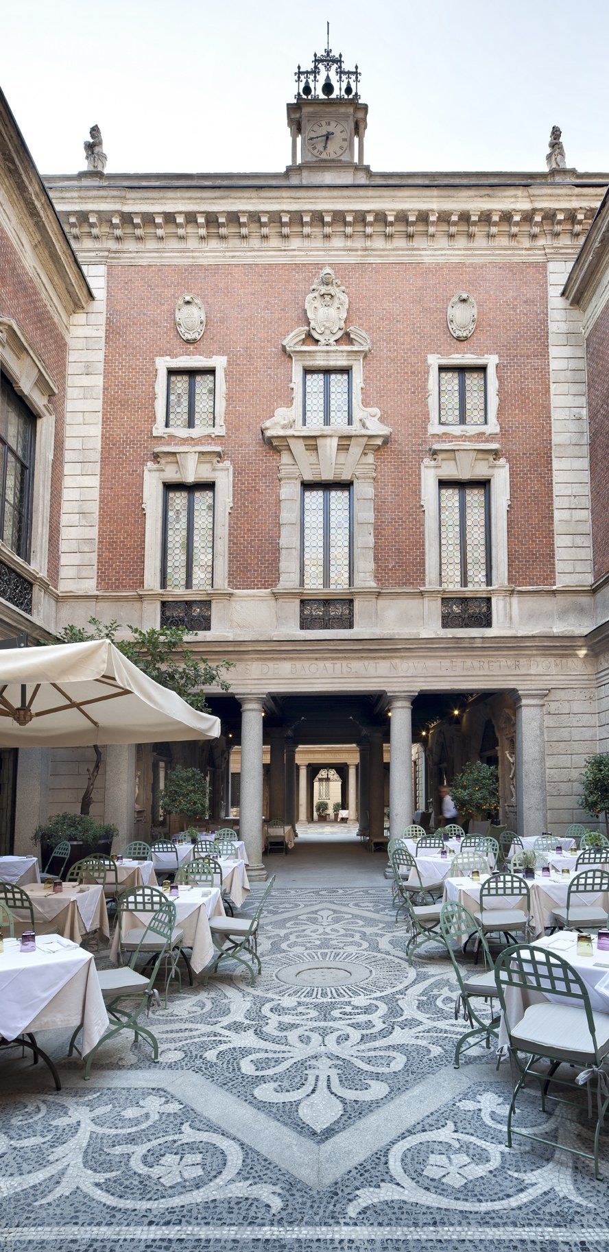 Un grande edificio in mattoni con tavoli e sedie davanti.