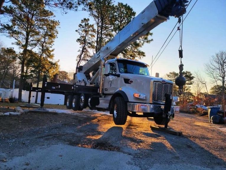 a bulldozer is hanging from a crane over a house .