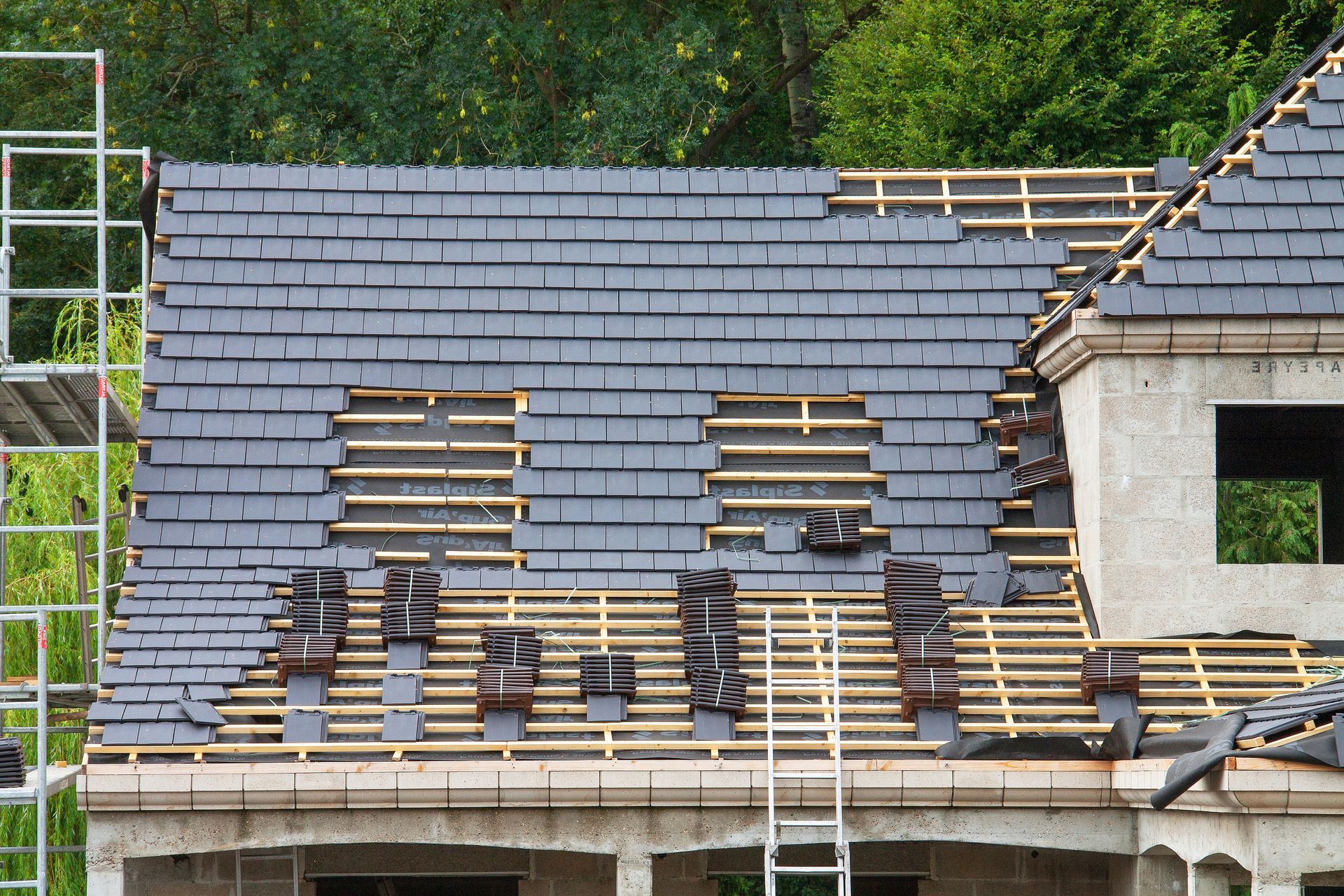 A roof is being built on a house with a ladder in the foreground