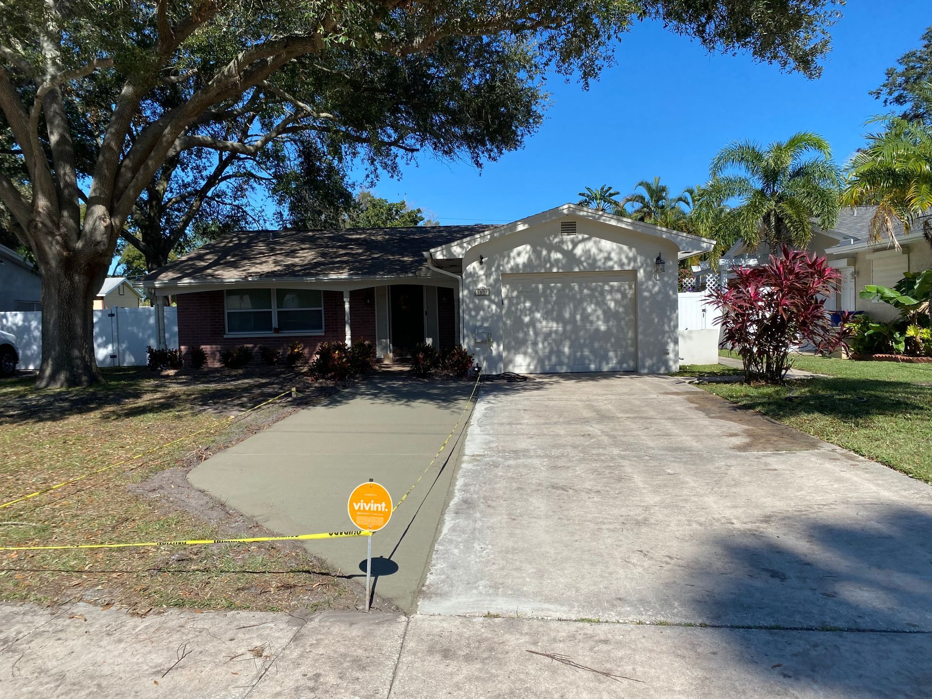 Concrete driveway with a new section, house in background. Sunny day.