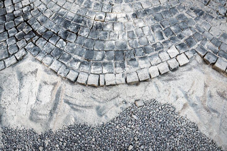 Cobblestone pavement construction with gray stone blocks and gravel.