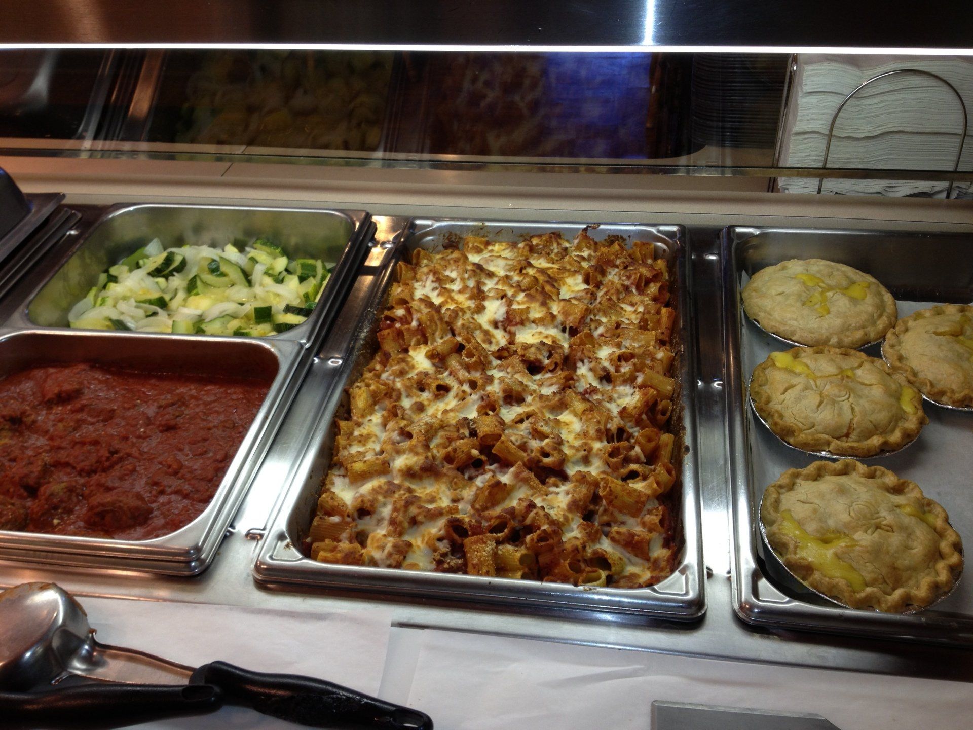 Several trays of food are displayed in a buffet line