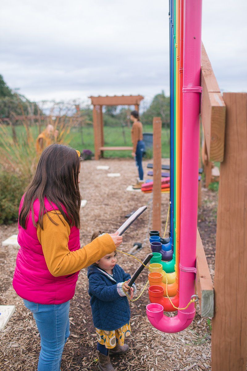 A woman and a child are playing with a colorful pipe.