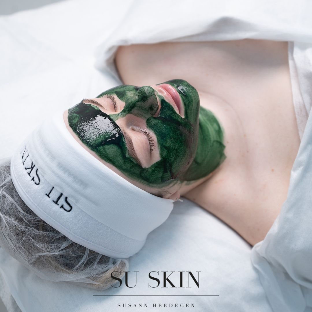 Eine Nahaufnahme des Auges einer Frau hinter einem grünen Blatt.