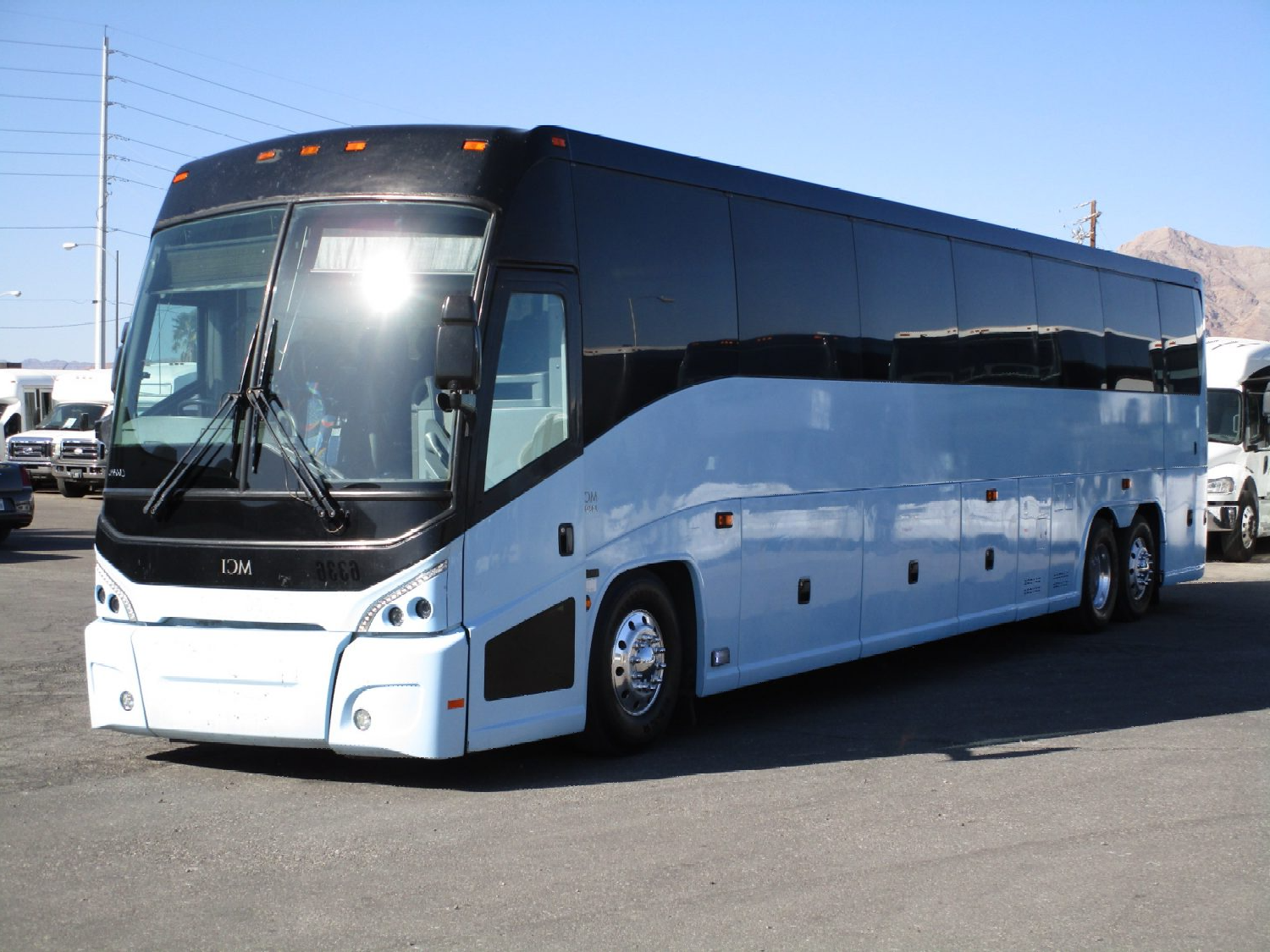 A large white and black bus is parked in a parking lot.