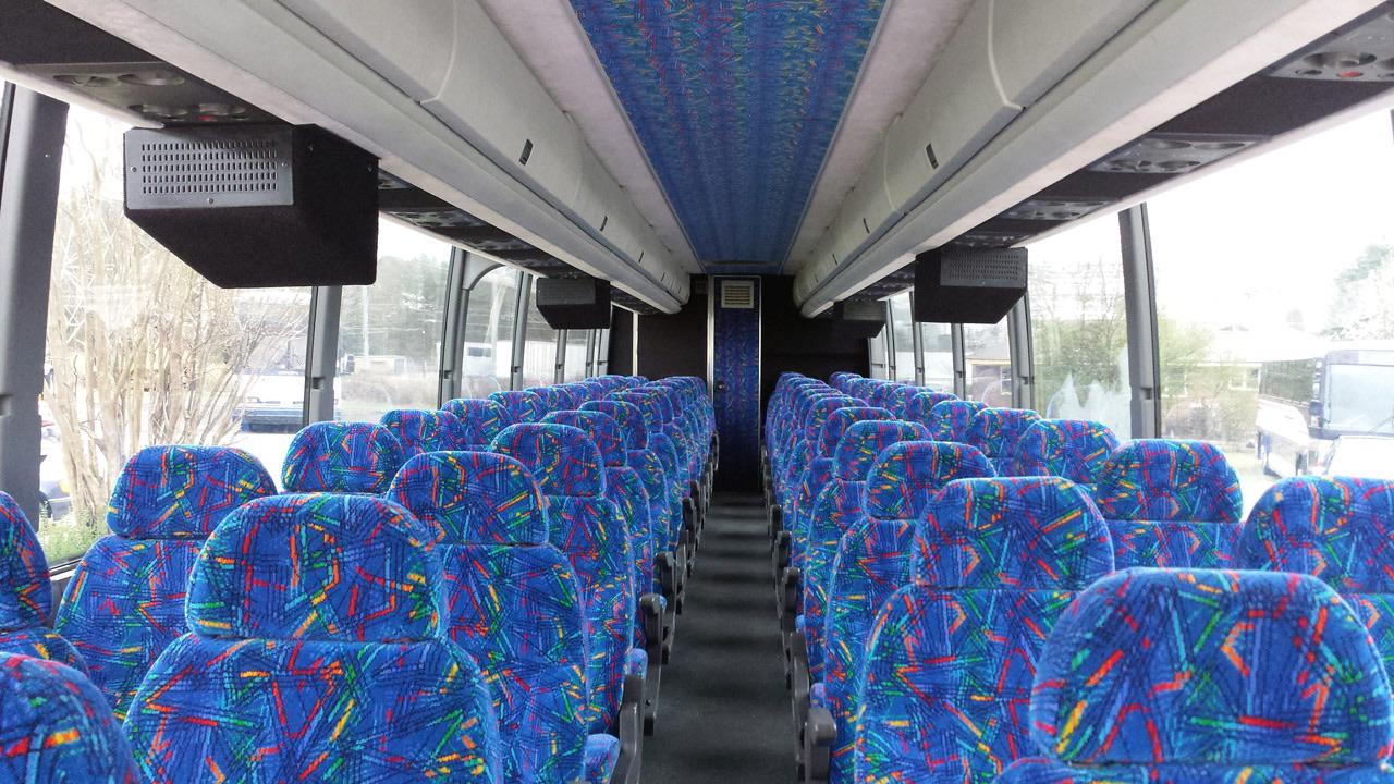 The inside of a bus with blue seats and a blue ceiling.