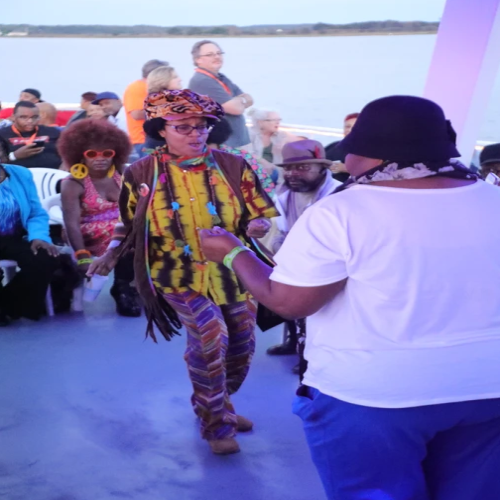 A group of people are dancing in front of a body of water. Eastern Shore Transportation LLC. 145 West Ostend St. Baltimore, Maryland 21230 1-800-689-6849