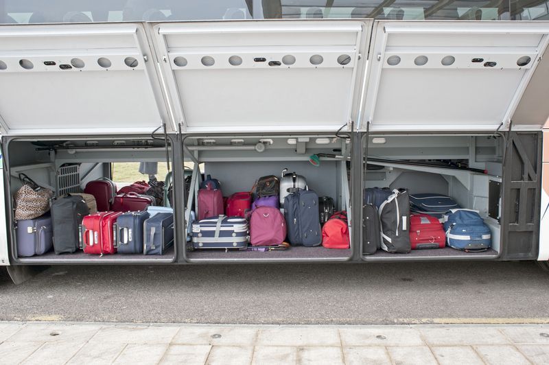 The back of a bus is filled with luggage.