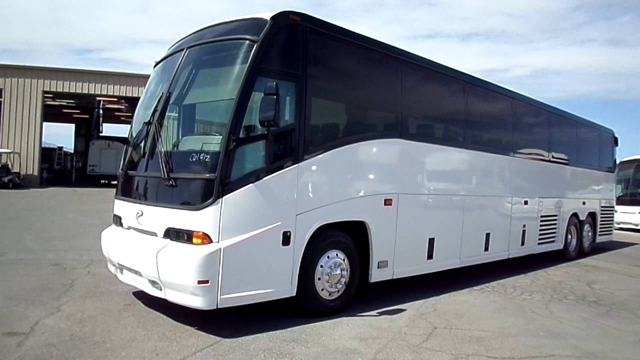 A white and black bus is parked in a parking lot