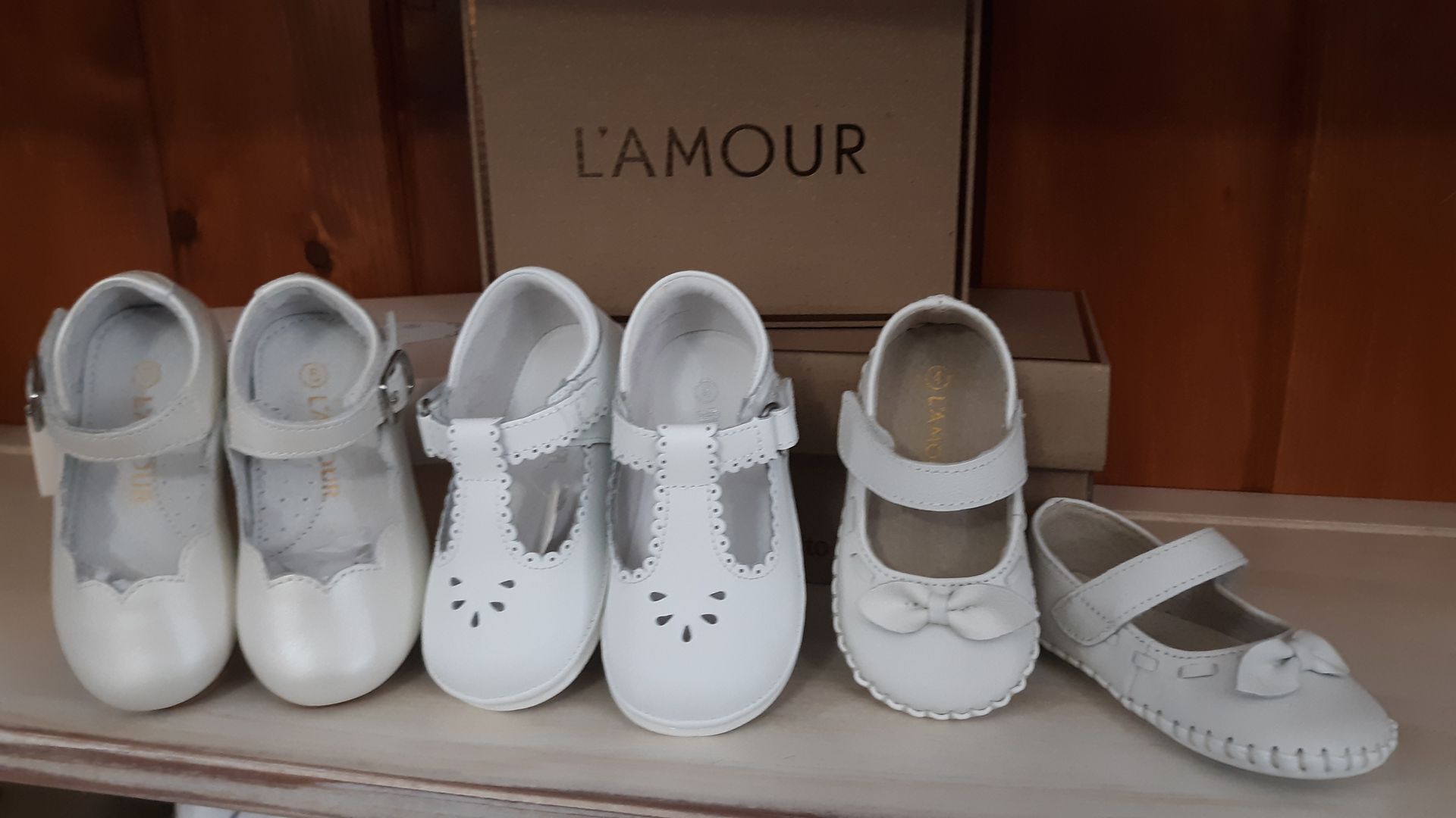 A row of white shoes are lined up in front of a box that says l' amour