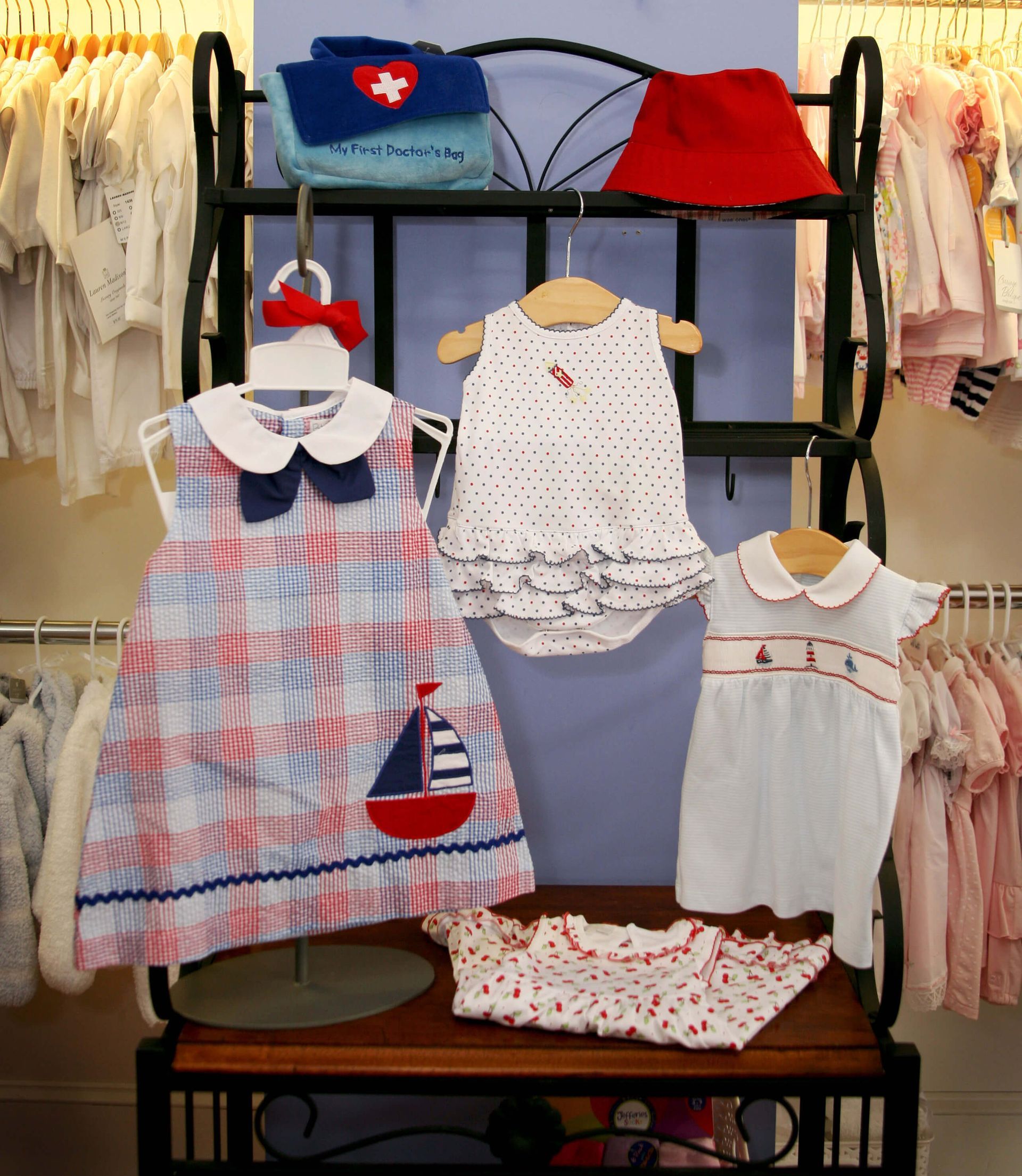 A display of children 's clothes including a dress with a sailboat on it