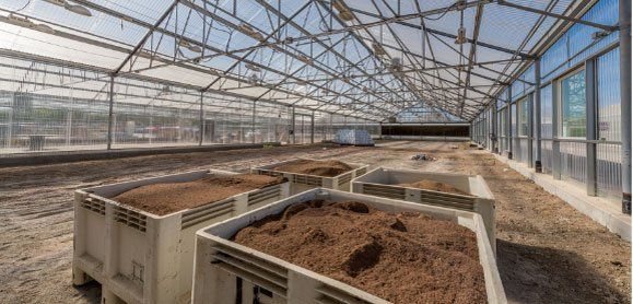 A greenhouse filled with lots of boxes of dirt.