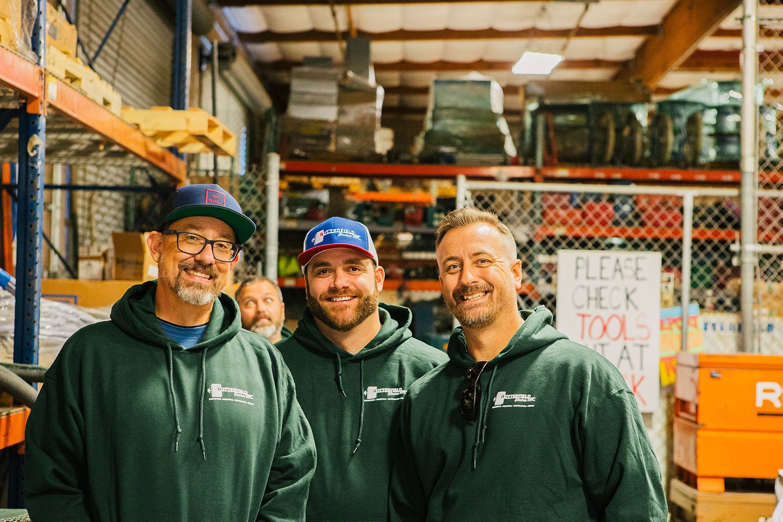 three men are posing for a picture in a warehouse .