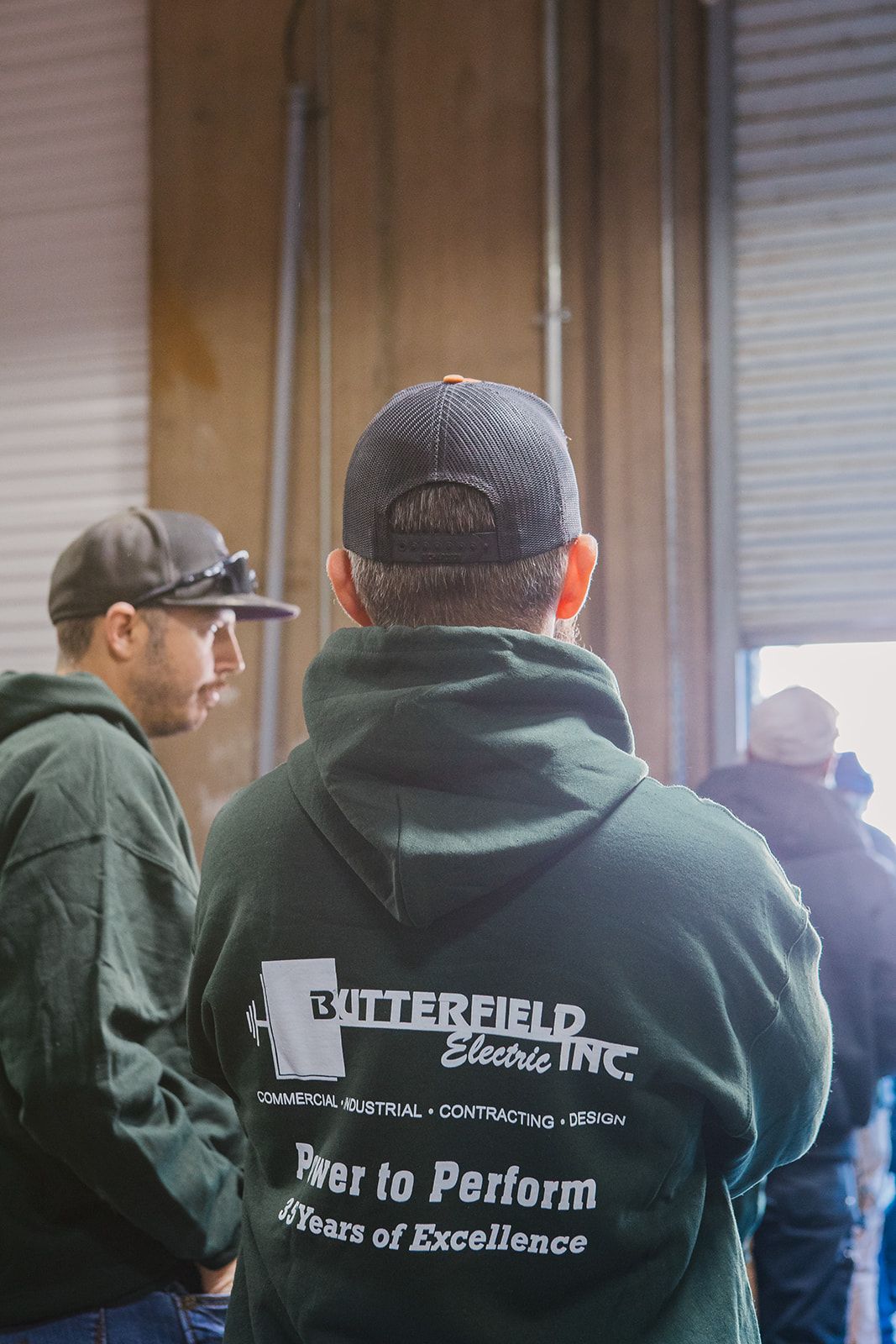 a man in a green hoodie is standing next to another man in a black hat .