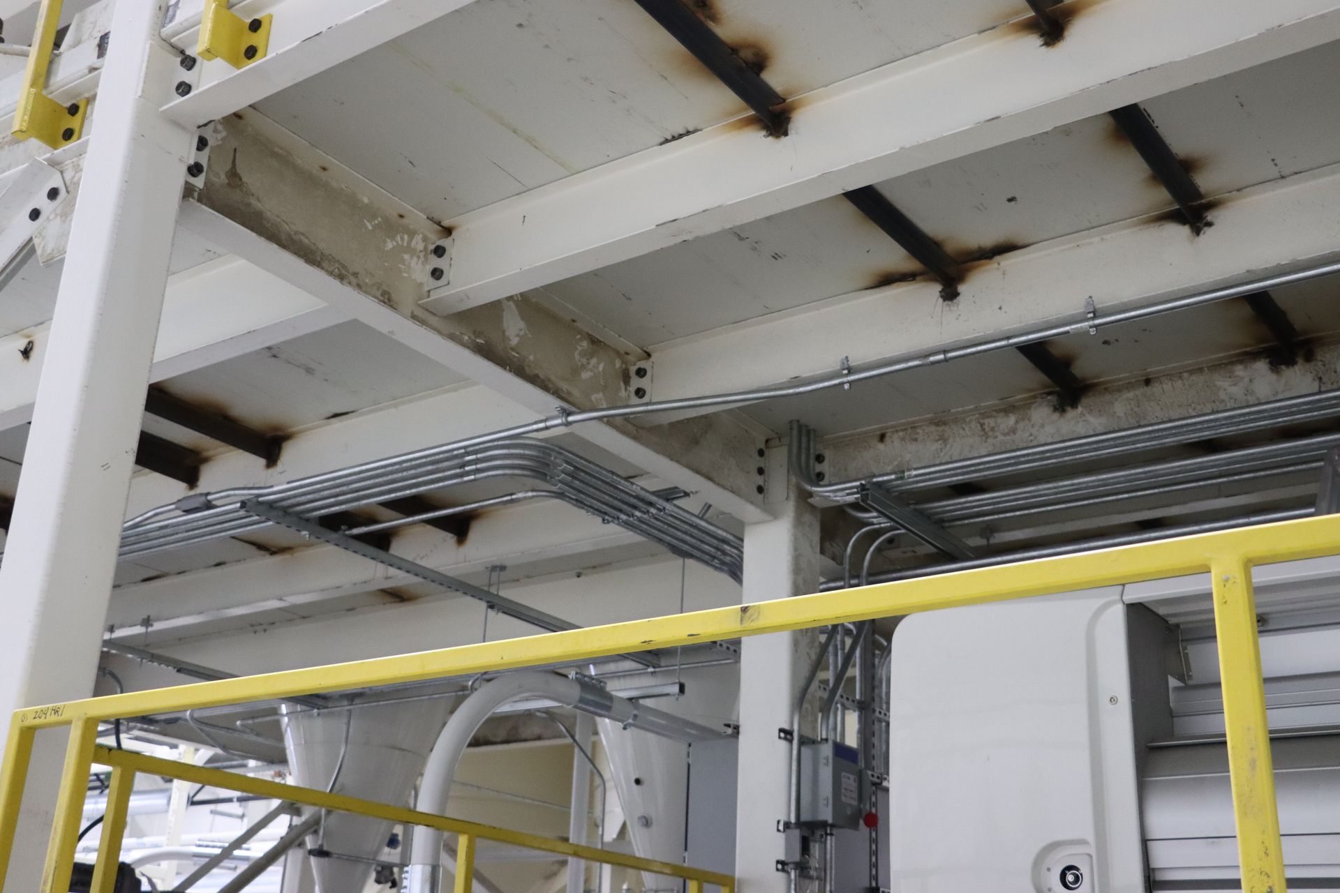 a white ceiling with a yellow railing in a factory