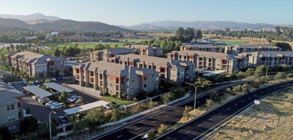 An aerial view of a large apartment complex with mountains in the background.