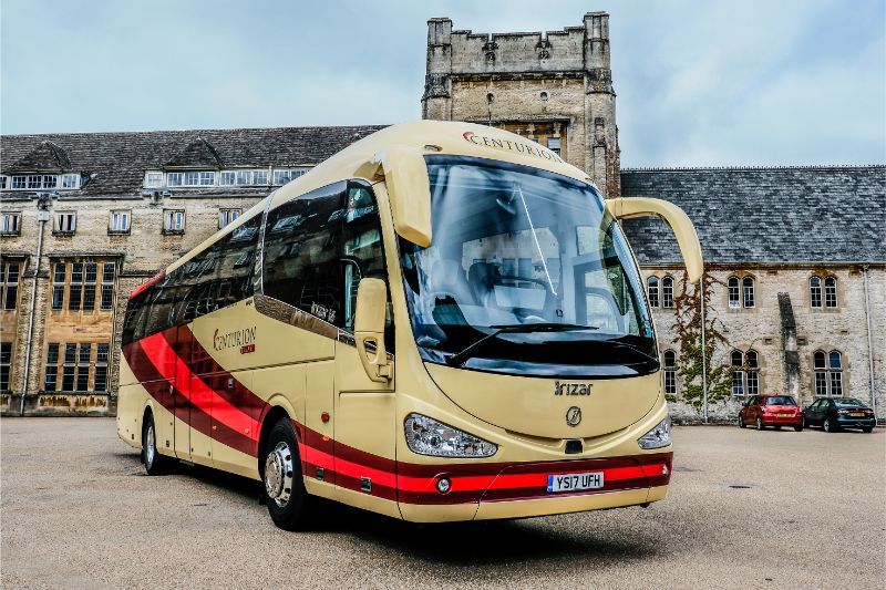 A yellow and red bus is parked in front of a building.