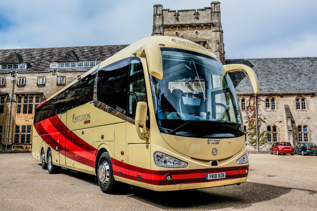 A large yellow and red bus is parked in front of a building.