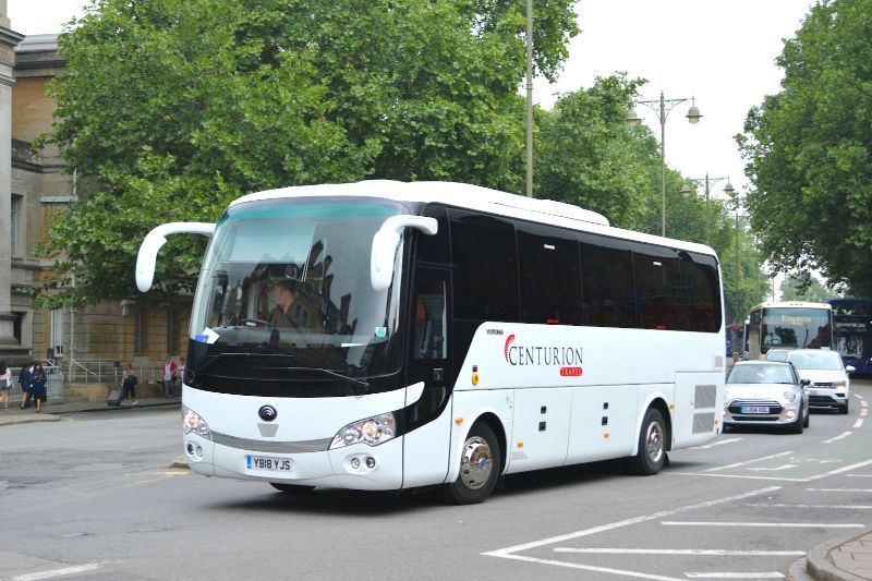 A white bus with the word centurion on the side is driving down a street.