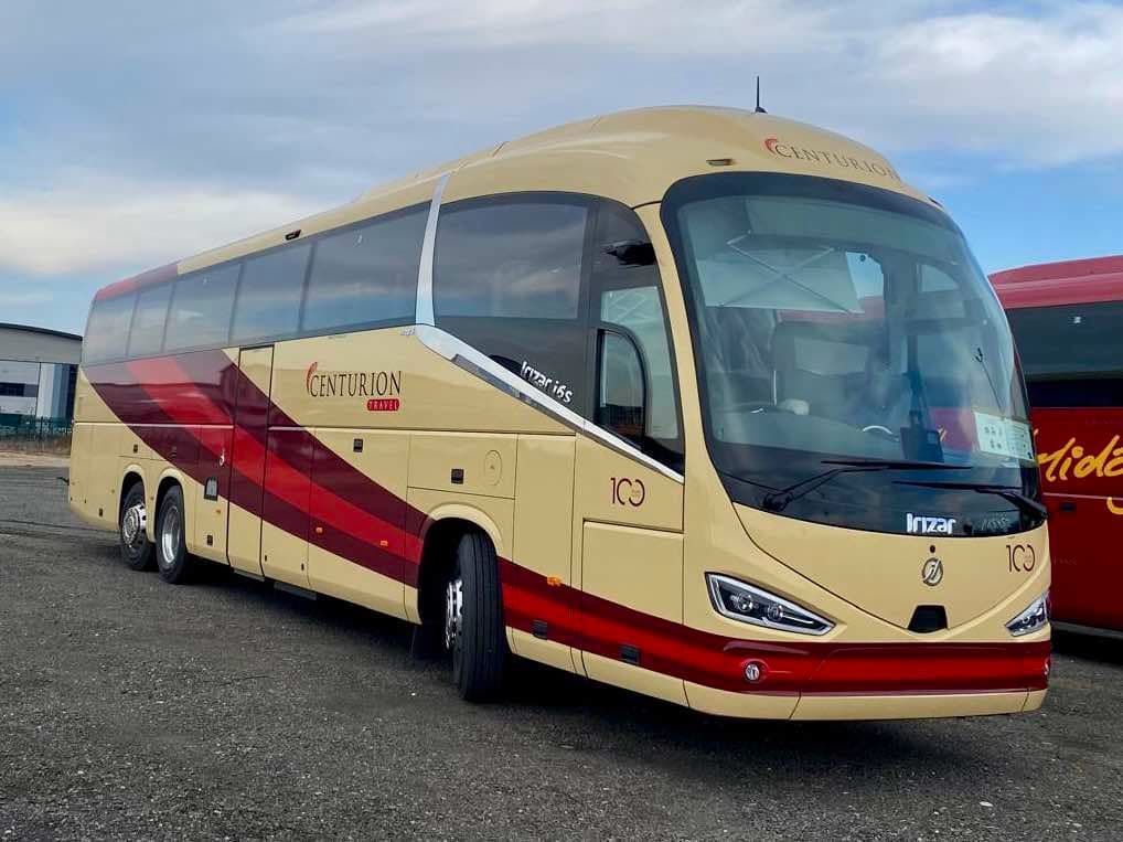 A yellow and red bus is parked in a parking lot.