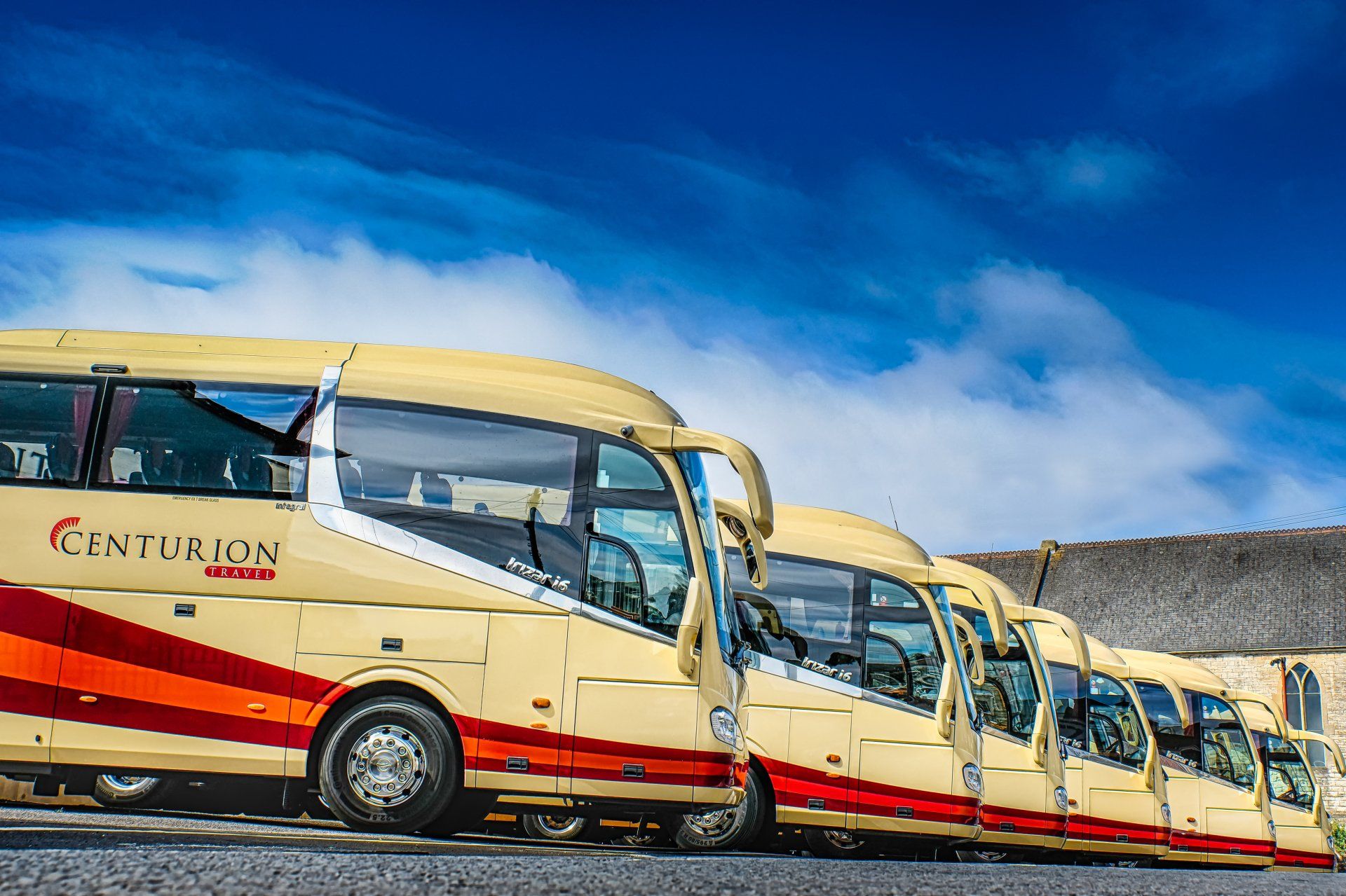 A row of buses parked next to each other in a parking lot.