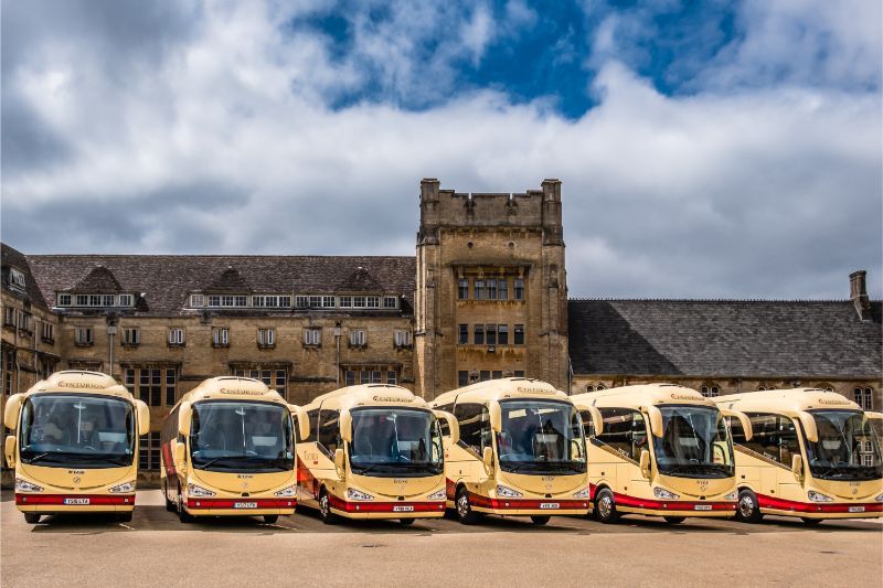 A row of buses are parked in front of a building.