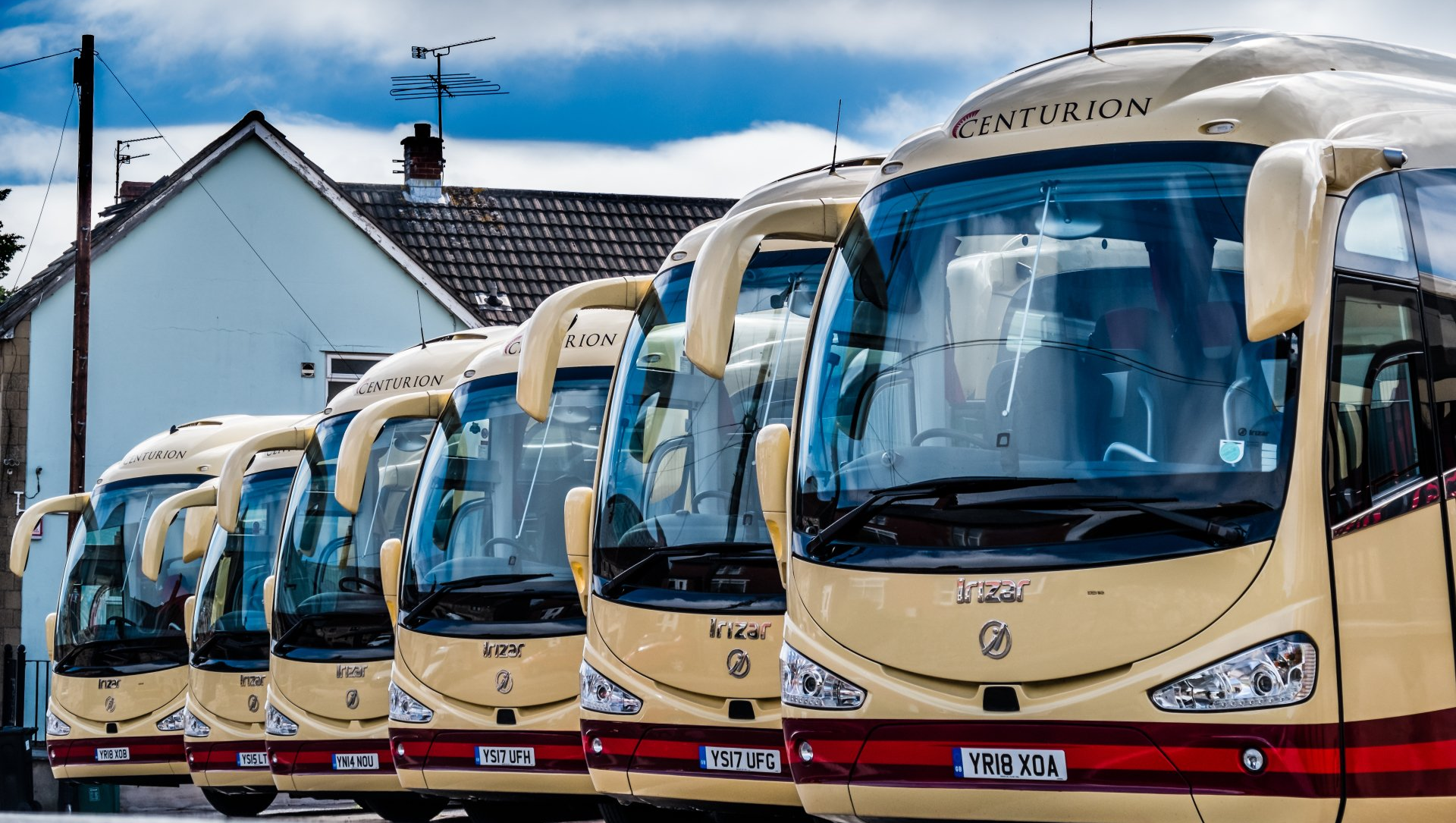 A row of buses are parked in front of a building.