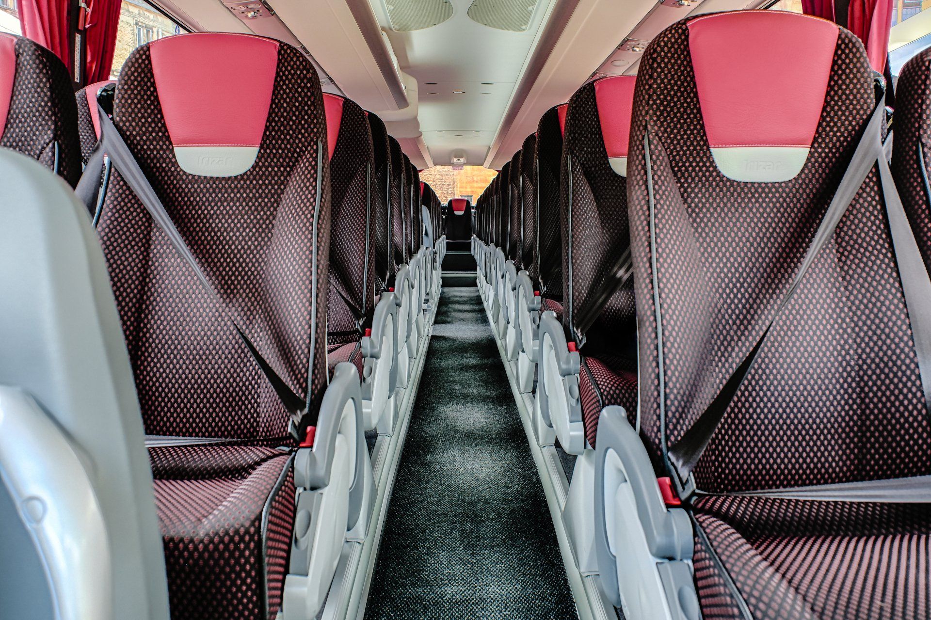 The inside of a bus with red and white seats.