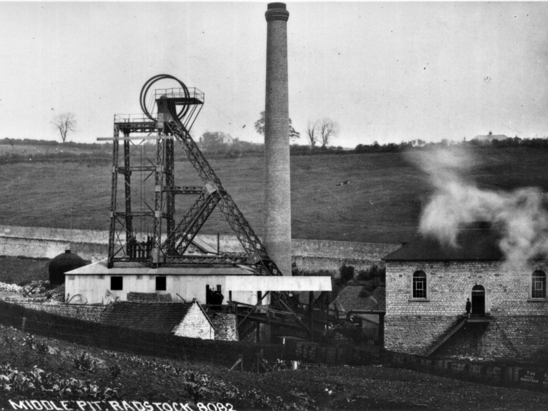 A black and white photo of a coal mine with a chimney