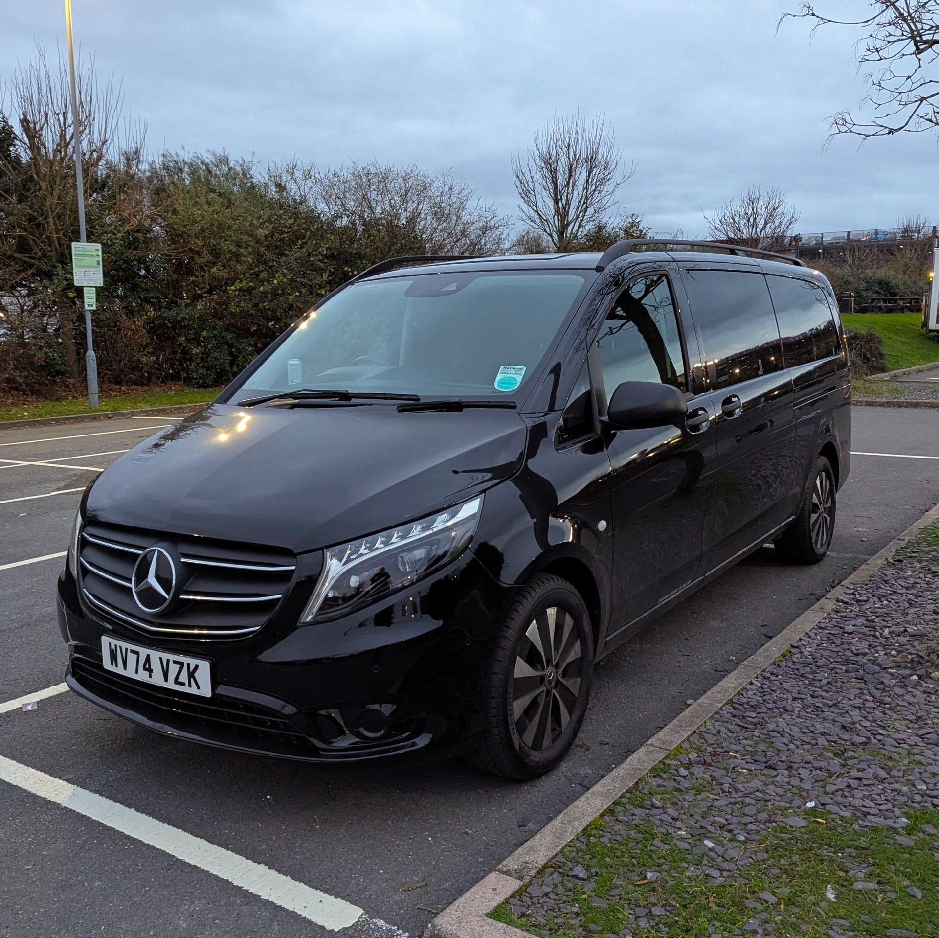 A black mercedes van is parked in a parking lot.