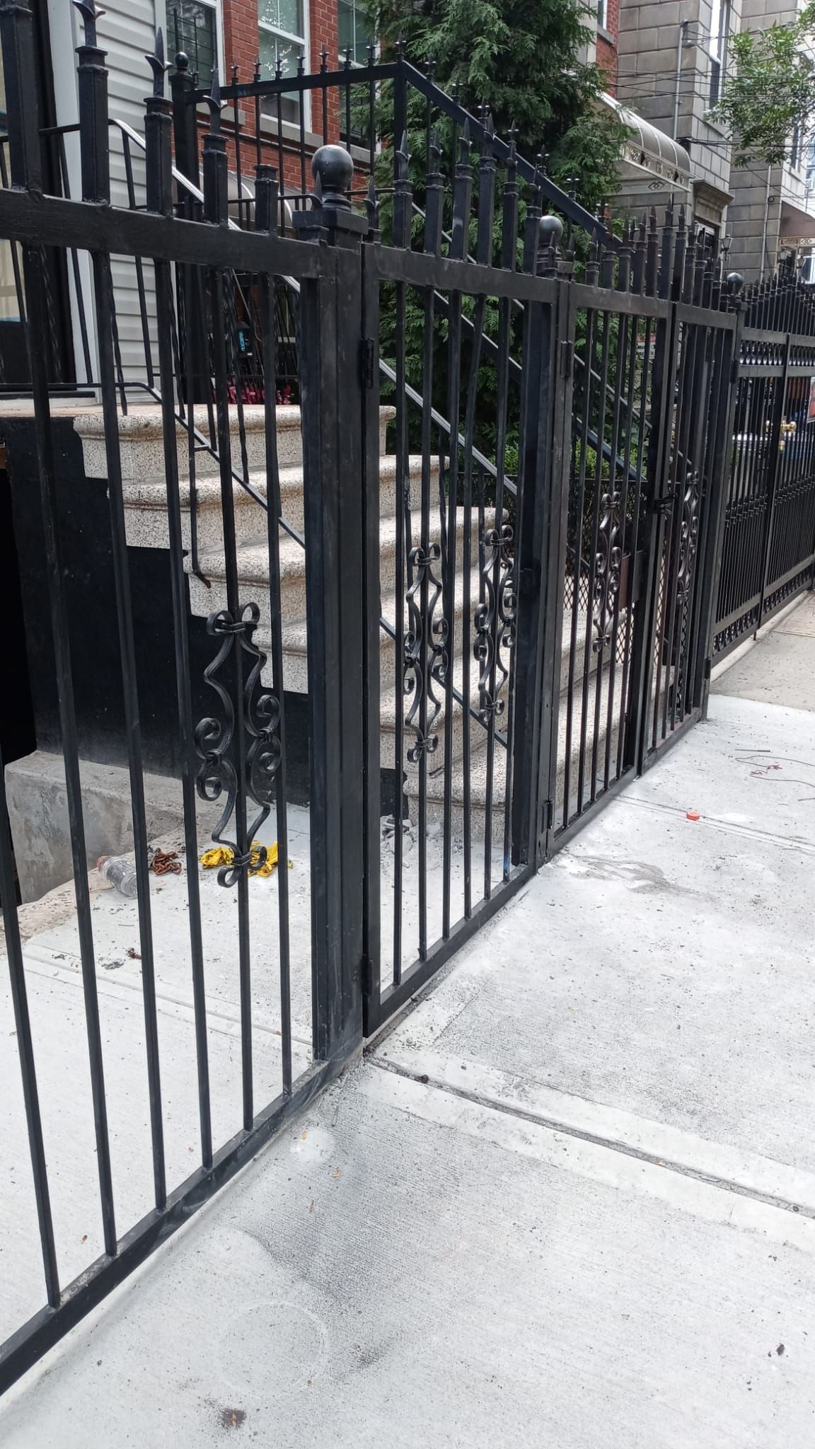 A black wrought iron fence surrounds a sidewalk and stairs.