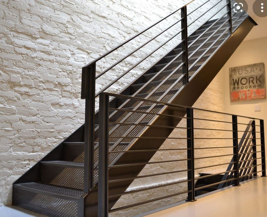 A staircase with a metal railing and a brick wall behind it.