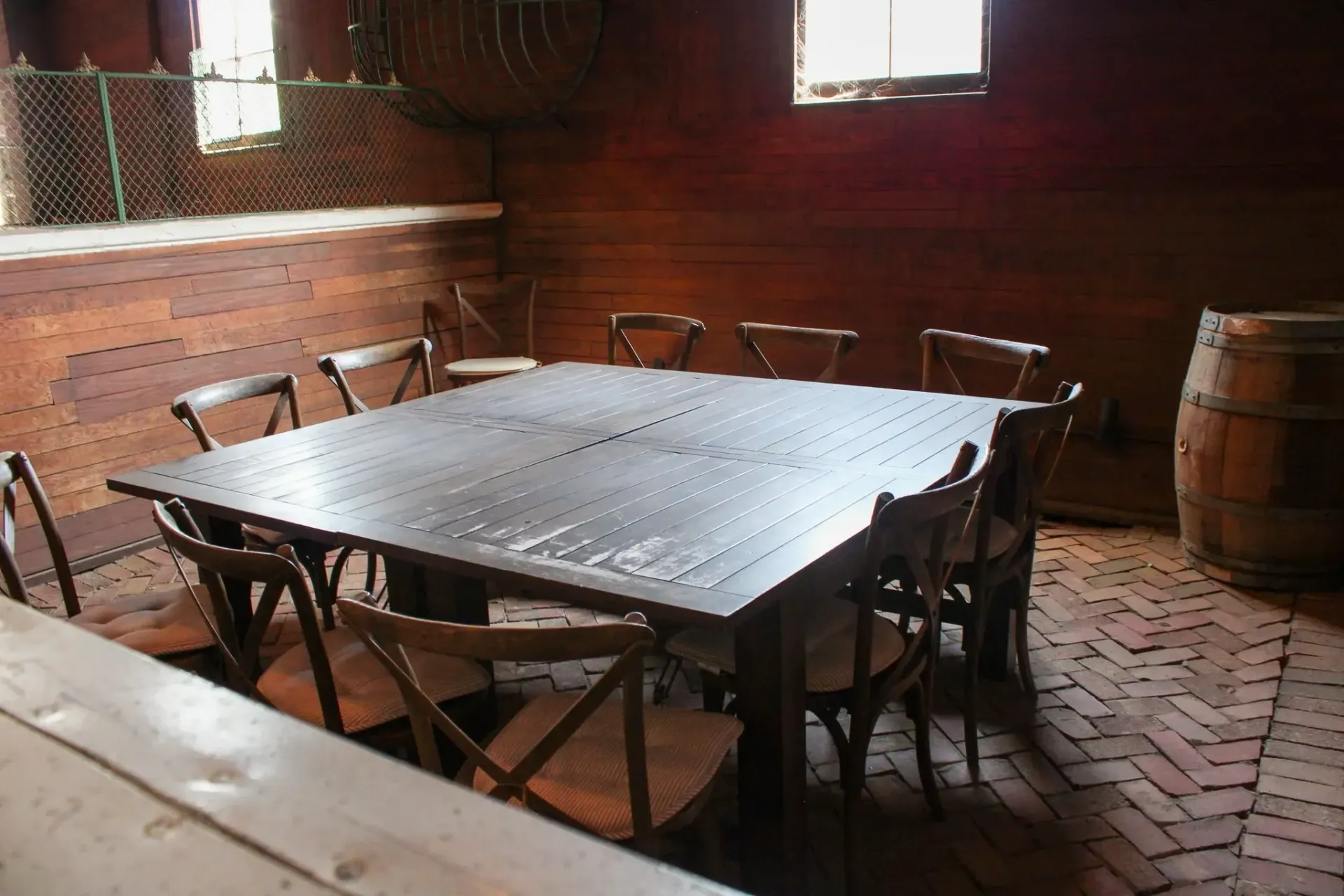 Wooden dining table with chairs set in a dimly lit room with a barrel.