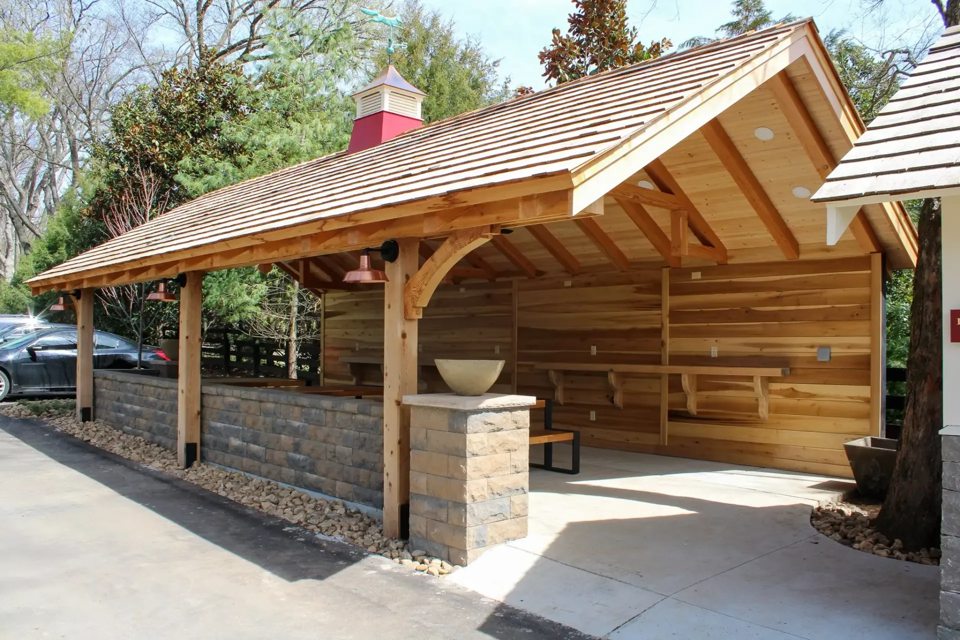 Wooden outdoor structure with stone accents, a sloped roof, and a cooking area.