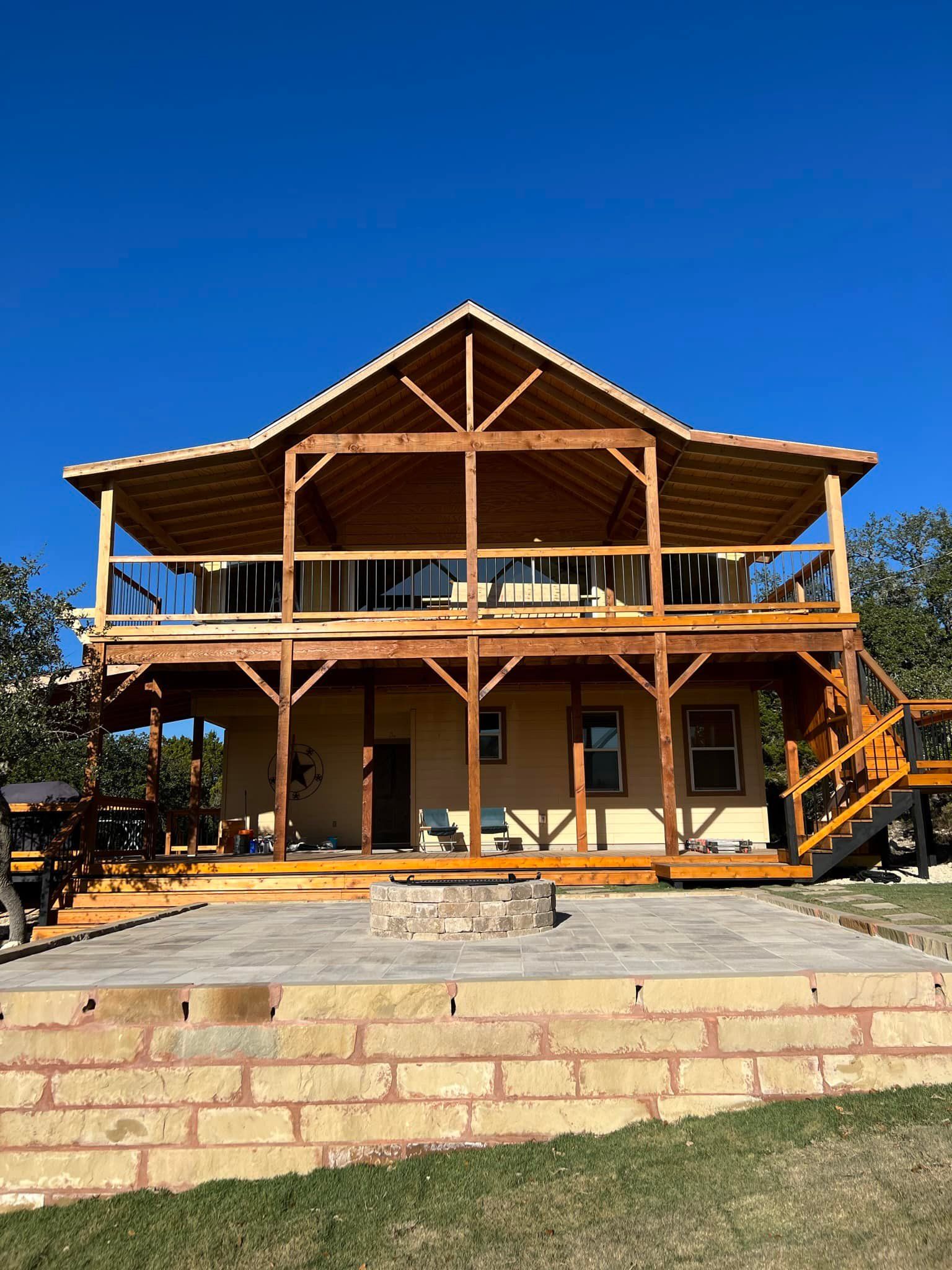 Two-story house with wooden balconies. Tan walls, brown trim. Blue sky.