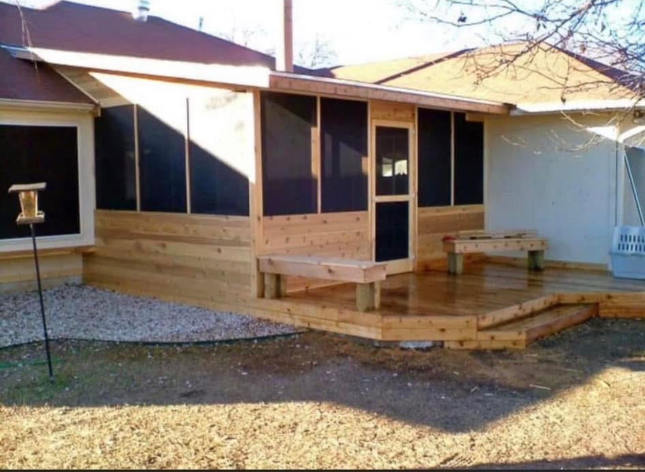 Wooden screened porch addition with attached benches and steps.