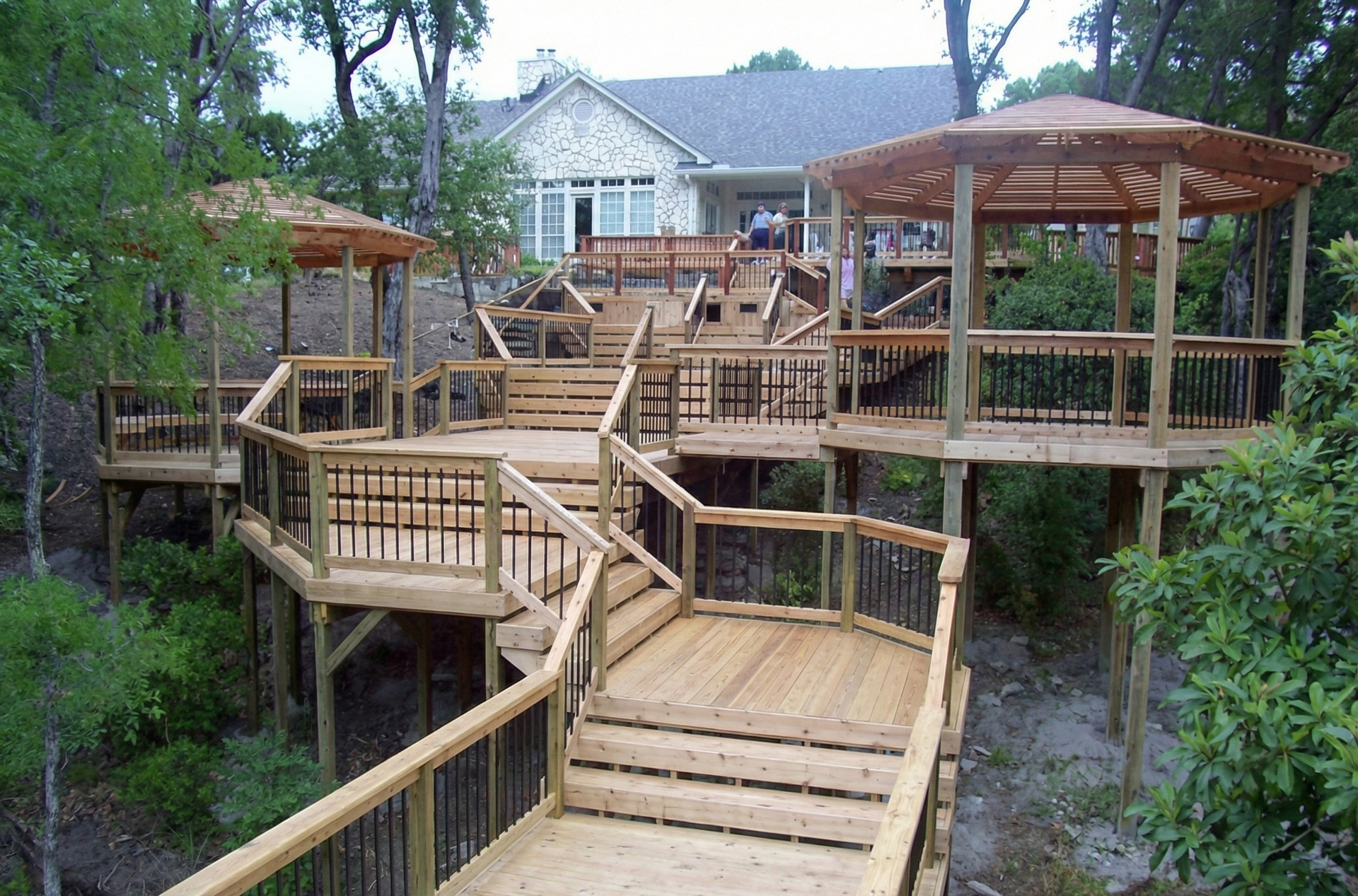Pergola over a patio, overlooking a pool and lush greenery.