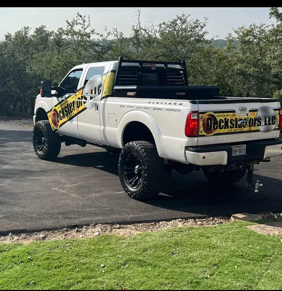 Wooden arbor with trellis sides and arched entry in a garden setting.