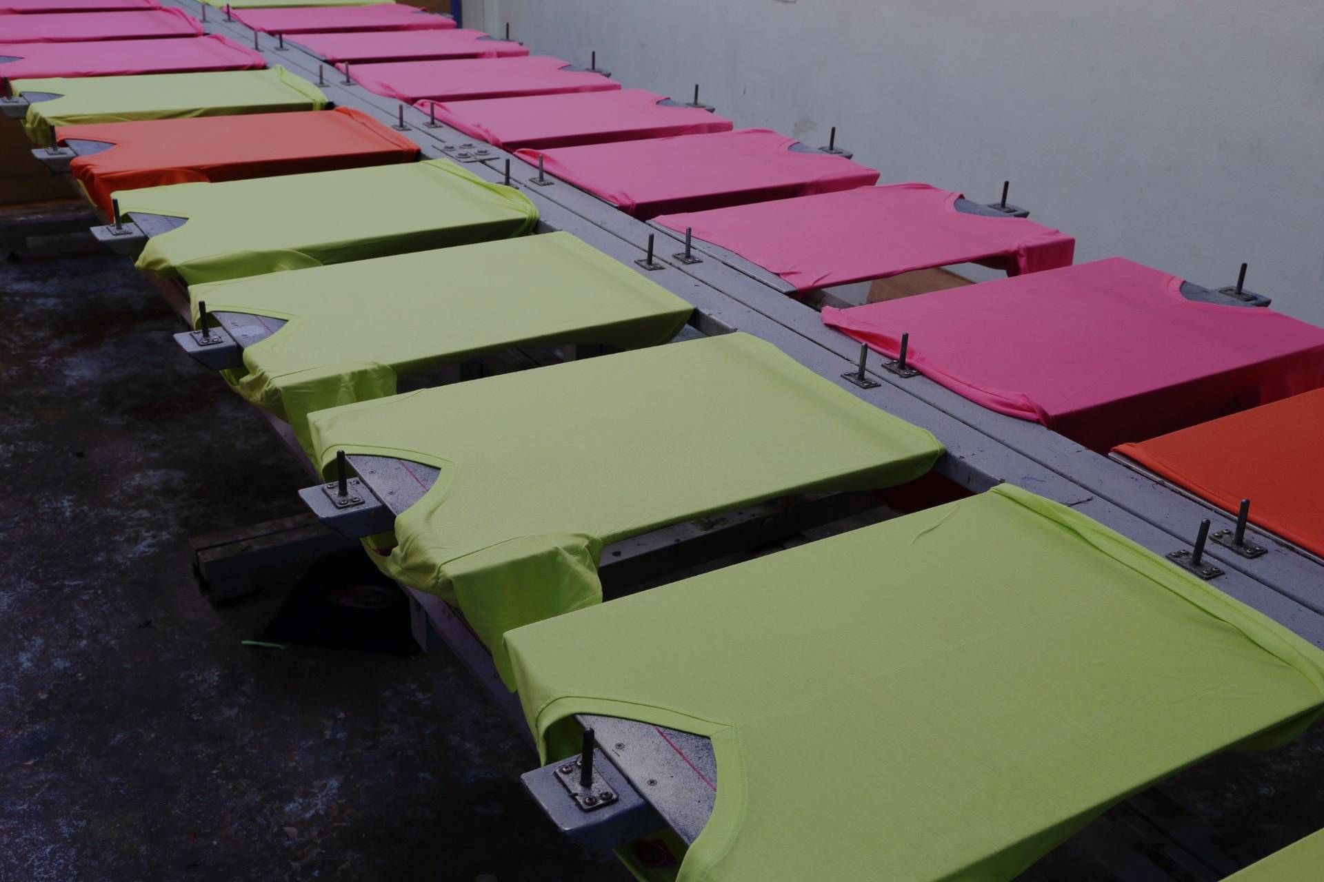 A row of colorful t-shirts are sitting on a conveyor belt.
